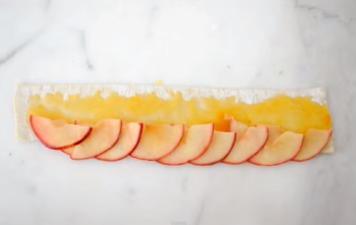 Stende uno strato di pasta sulle mele, il risultato è delizioso