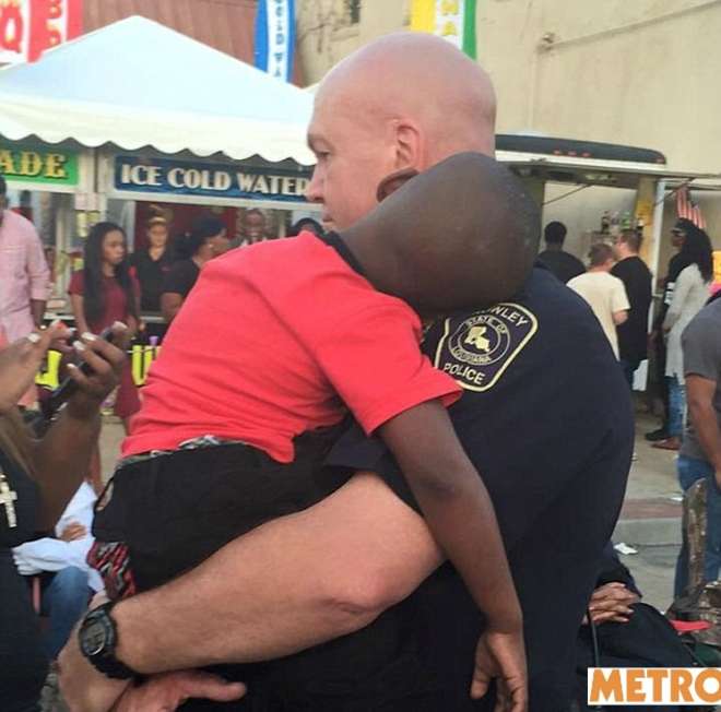 Poliziotto tiene in braccio un bimbo, la foto sta commuovendo il web: ecco perchè